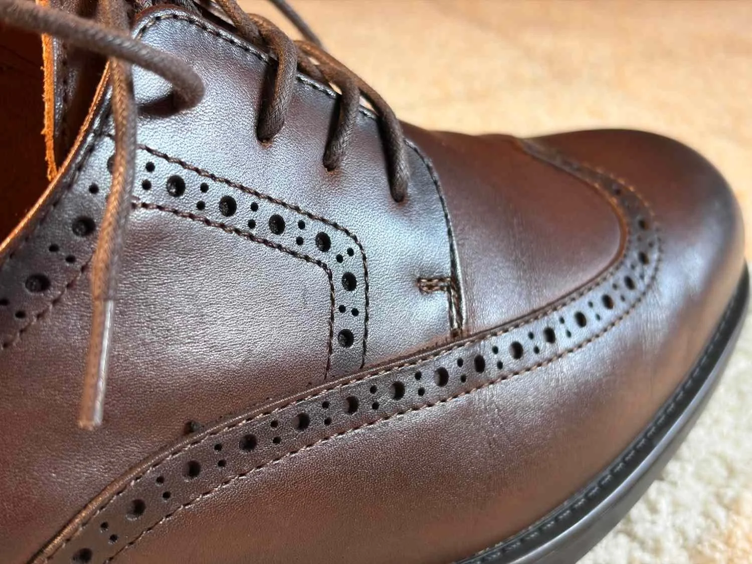 Close-up of Bruno Marc brown leather brogues showing the leather grain, stitching and decorative brogue perforations.