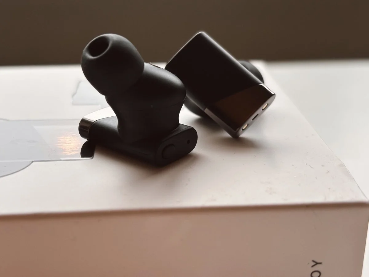 Status Pro X earbuds close-up showing matte black finish