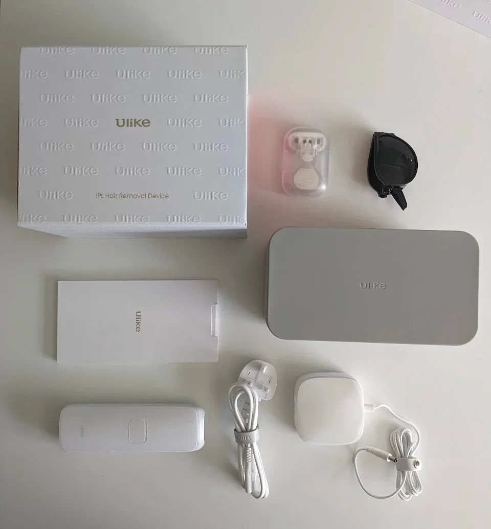 An overhead shot of the Ulike Air 3 IPL Hair Removal Device unboxed with its accessories on a white table.