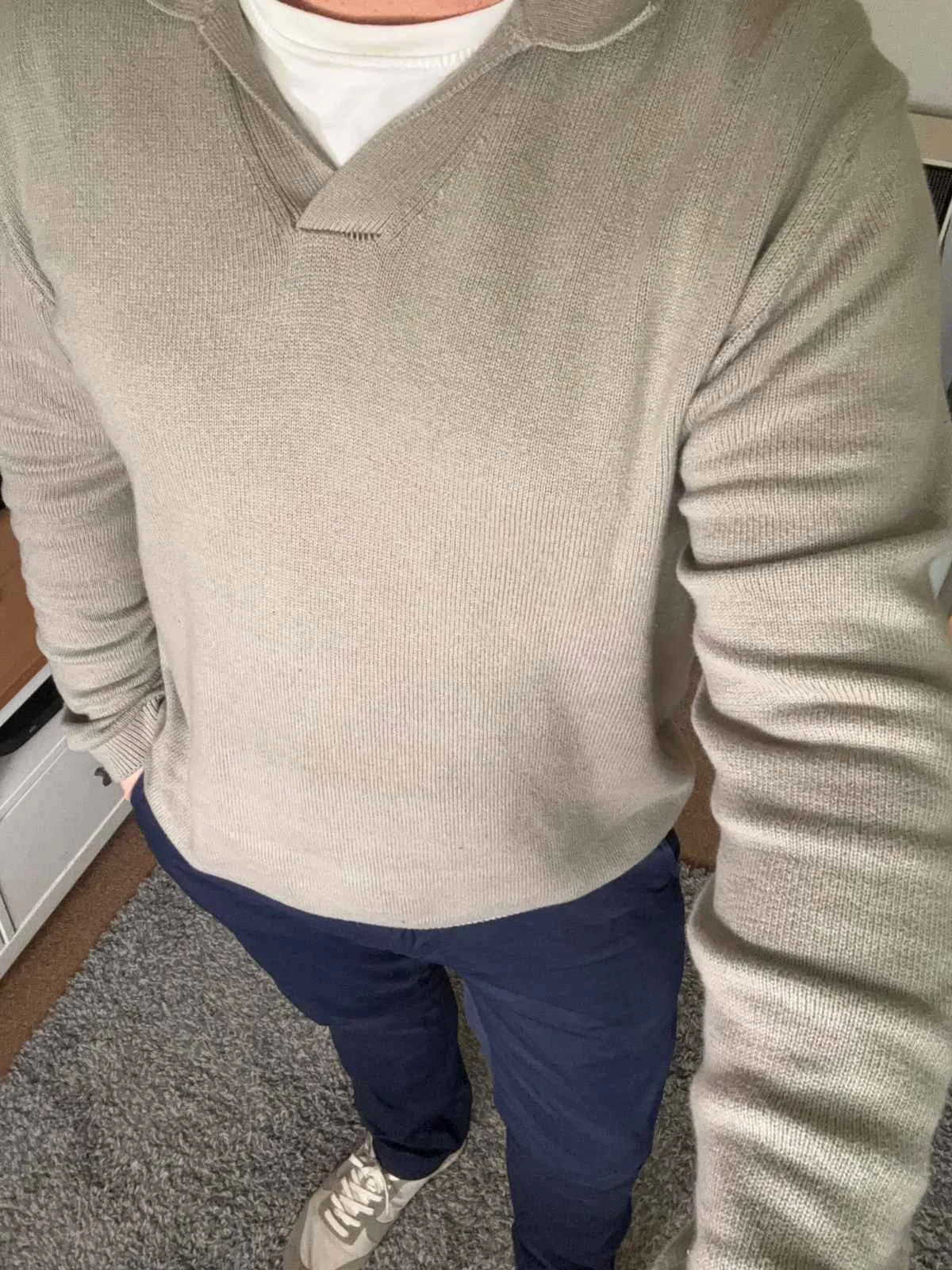 Angled smart-casual outfit shot featuring Tailor Vintage navy slim fit chinos with a beige knit top and trainers