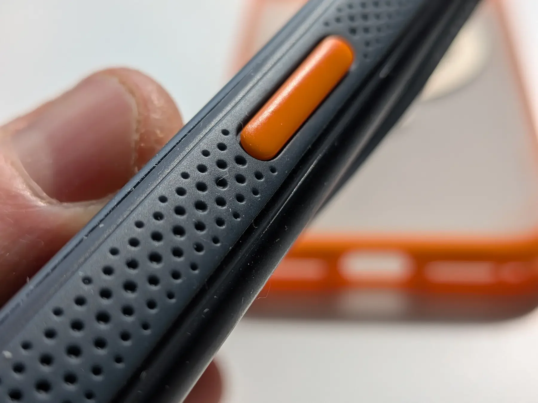 Macro shot of the orange side button and dotted grip texture on the TORRAS Ostand Q3 Air case for iPhone 17 Pro Max