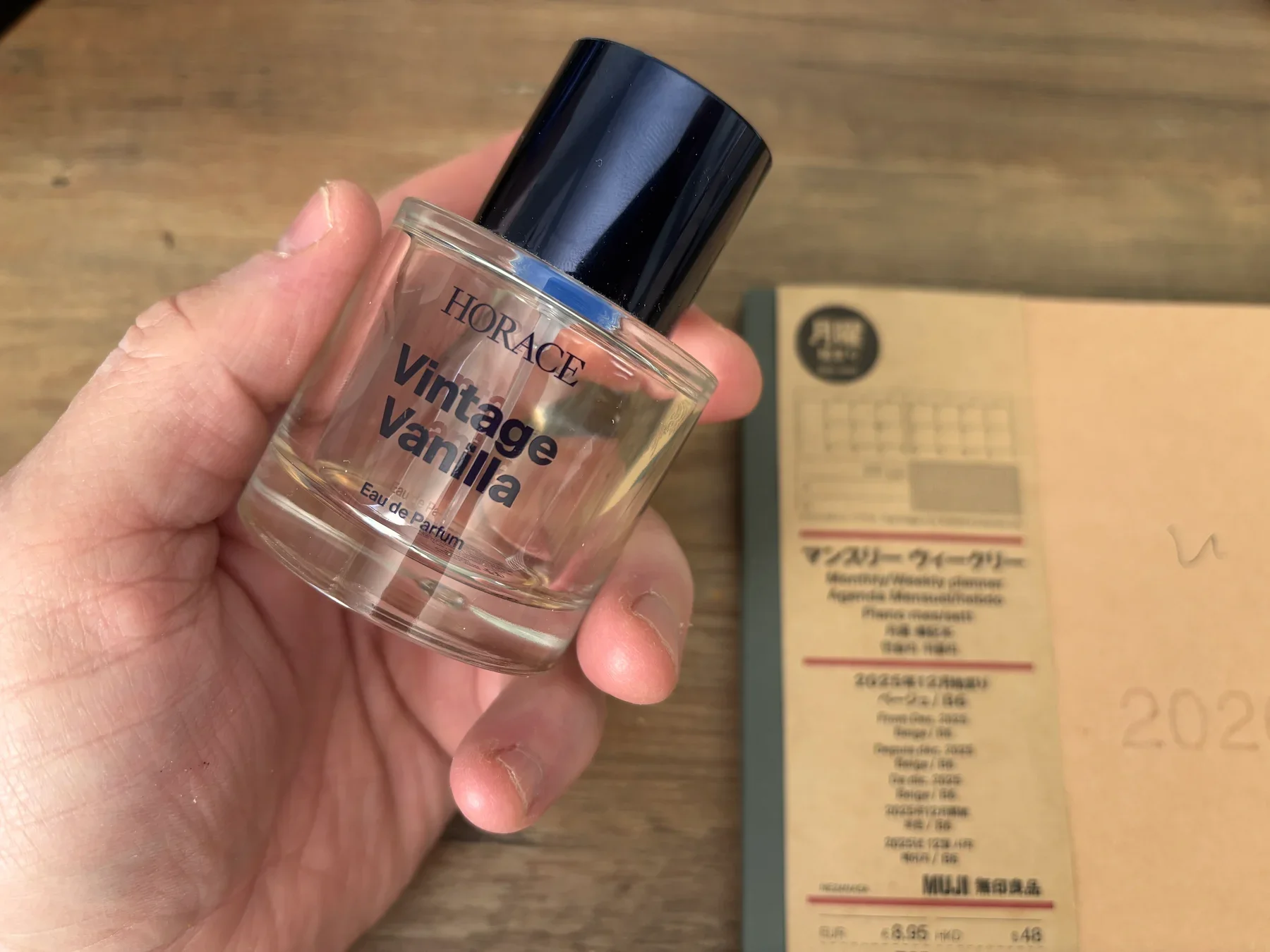 Jerome holding a bottle of Horace Vintage Vanilla Eau de Parfum over his desk and MUJI planner in his Bristol home office.