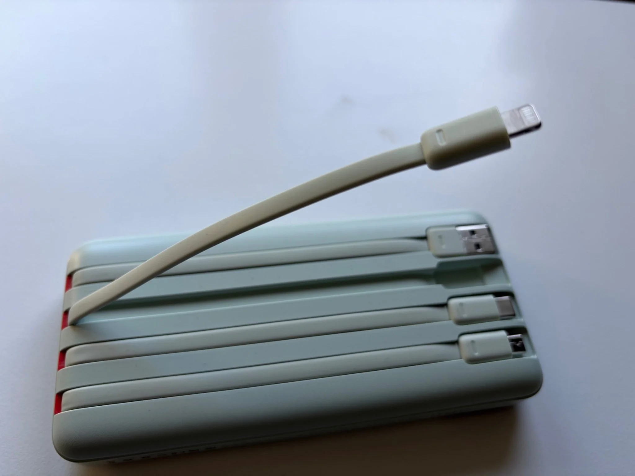 Charmast 20000mAh power bank with its integrated Lightning charging cable extended.