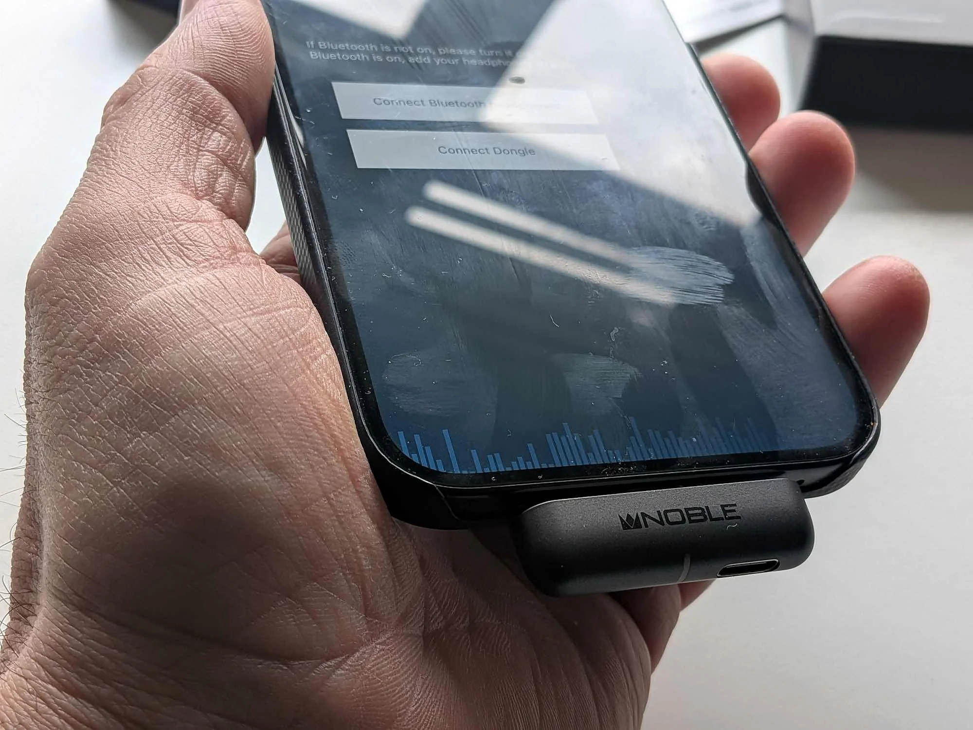 Noble Sceptre USB-C dongle connected to a phone, held in hand.