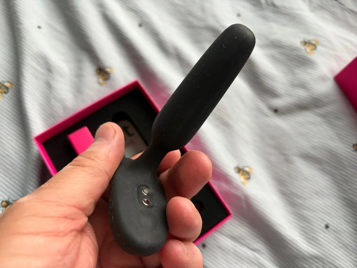 Lovense Glint black silicone vibrating butt plug held in one hand to demonstrate its compact size.