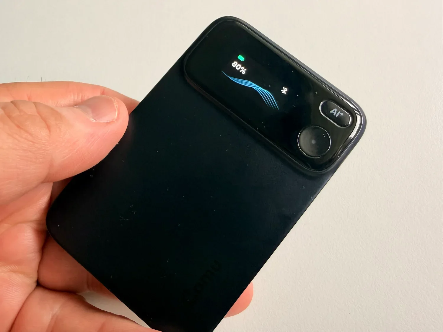 Close-up of the Comu Action Pro showing its small display, battery level and AI button.