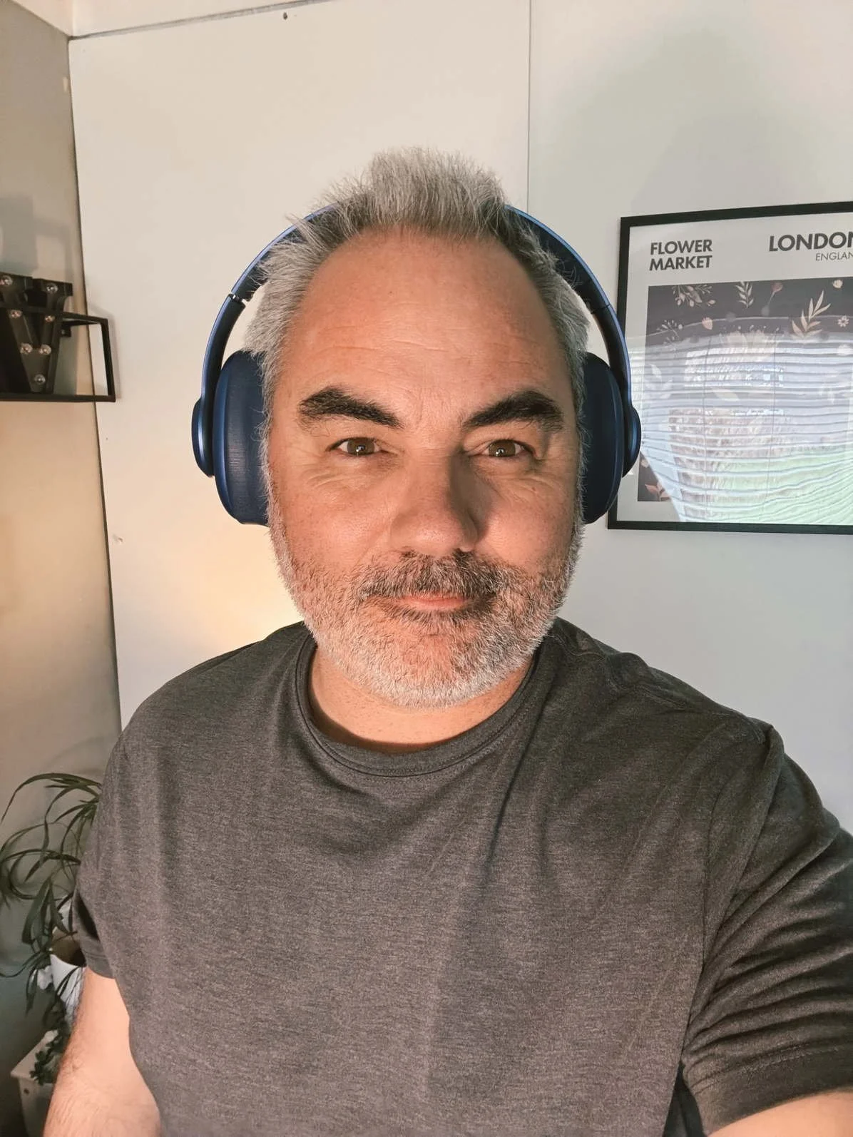 Man wearing Fresh ’n Rebel Clam Ace 2 over-ear headphones in blue, close-up portrait indoors.