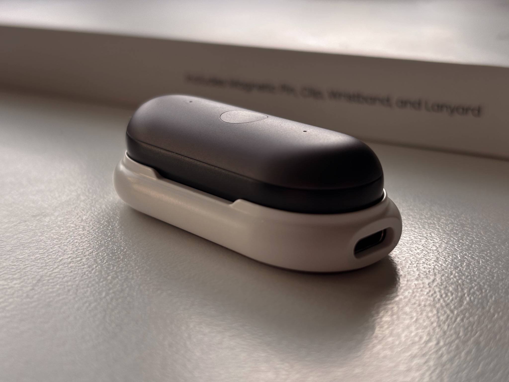 PLAUD NotePin S resting on its charging dock, showing the compact design and USB-C charging.