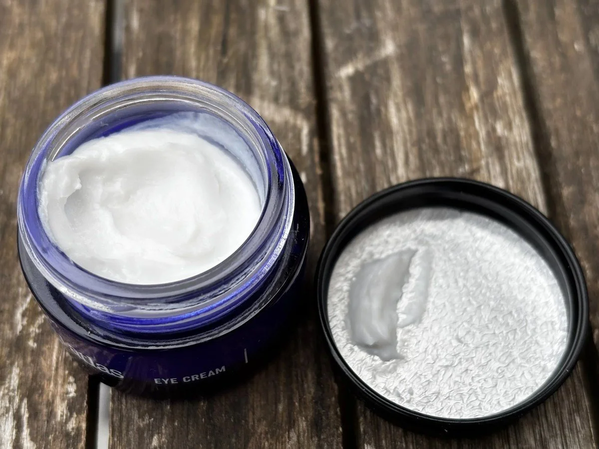 Open Blu Atlas Eye Cream jar showing the cream texture on a wooden table with the lid beside it