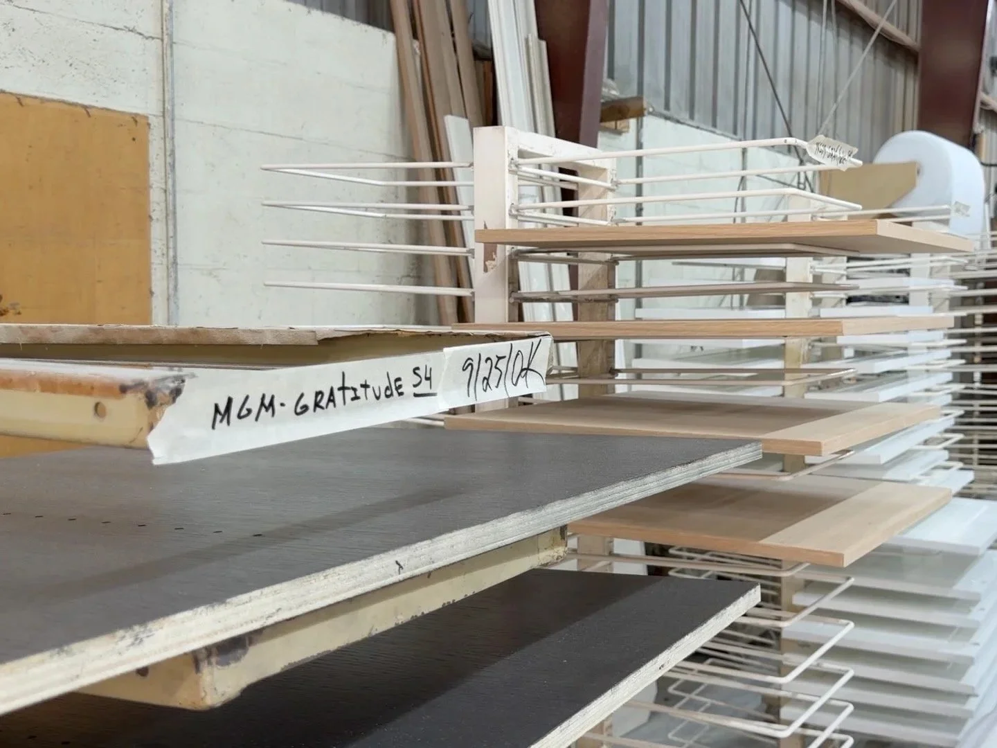 Various wooden and plastic panels stored on metal racks in a warehouse or workshop.