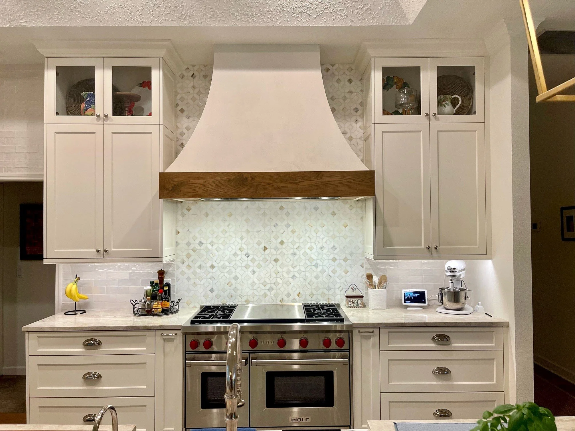 White kitchen with upper cabinets, a stove, and decorative items on the counter.