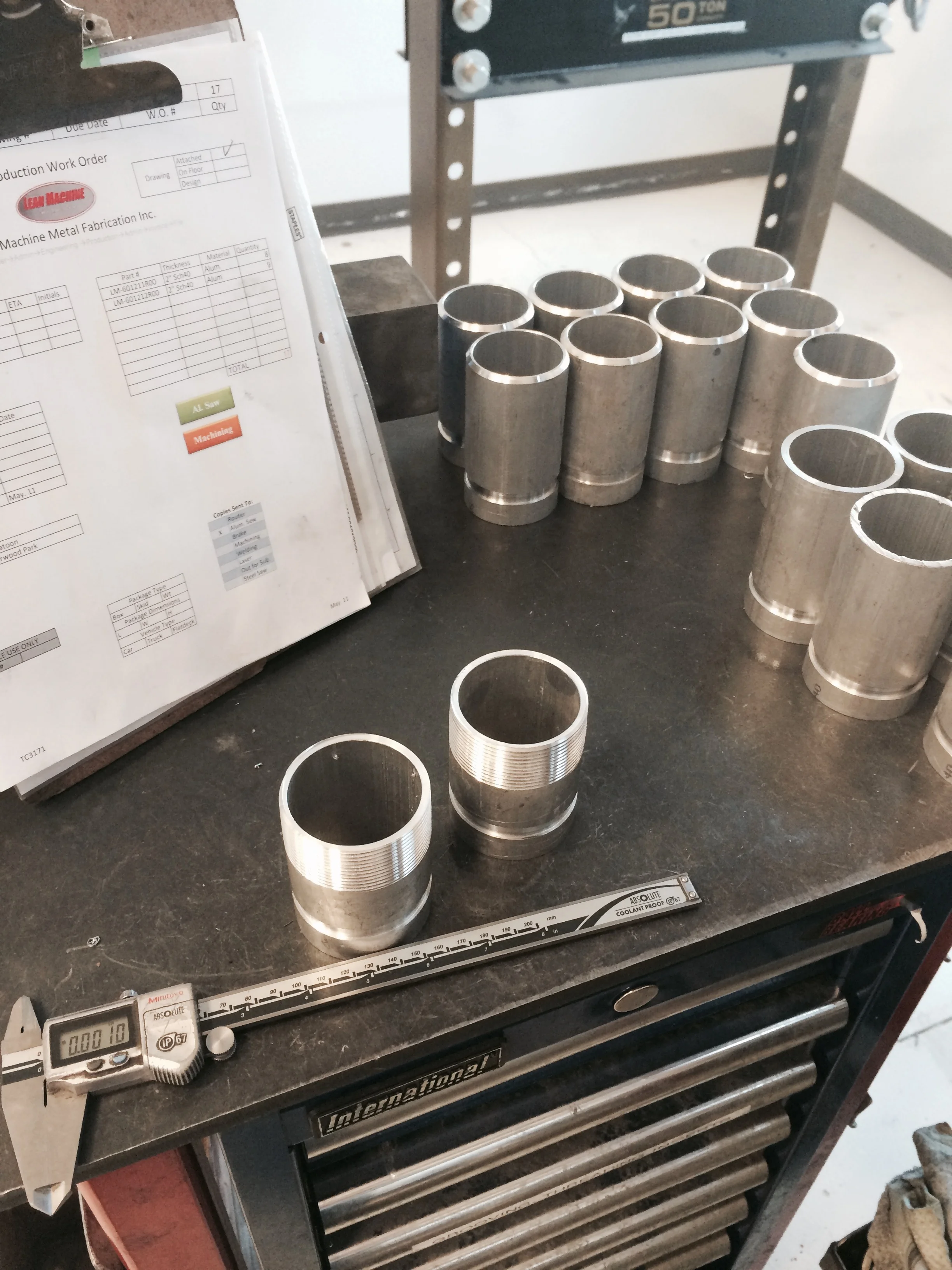 Here are some pipe fittings coming out of the machining process being quality checked for accuracy. The ones in front are Vic groove x threaded. The fittings in the background are Vic groove x weld bevel. If you zoom in you get a neat shot of a Lean Machine production work order.