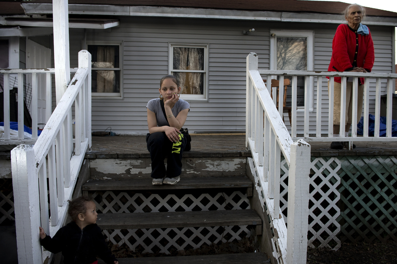  Sarai Huertas sits for a portrait on the back steps of her mother's house while her grandmother, Francisca Navarro Roman, and her youngest son, Cheniel Huertas, look on. Huertas lives in a house with her children and the biological father of Cheniel