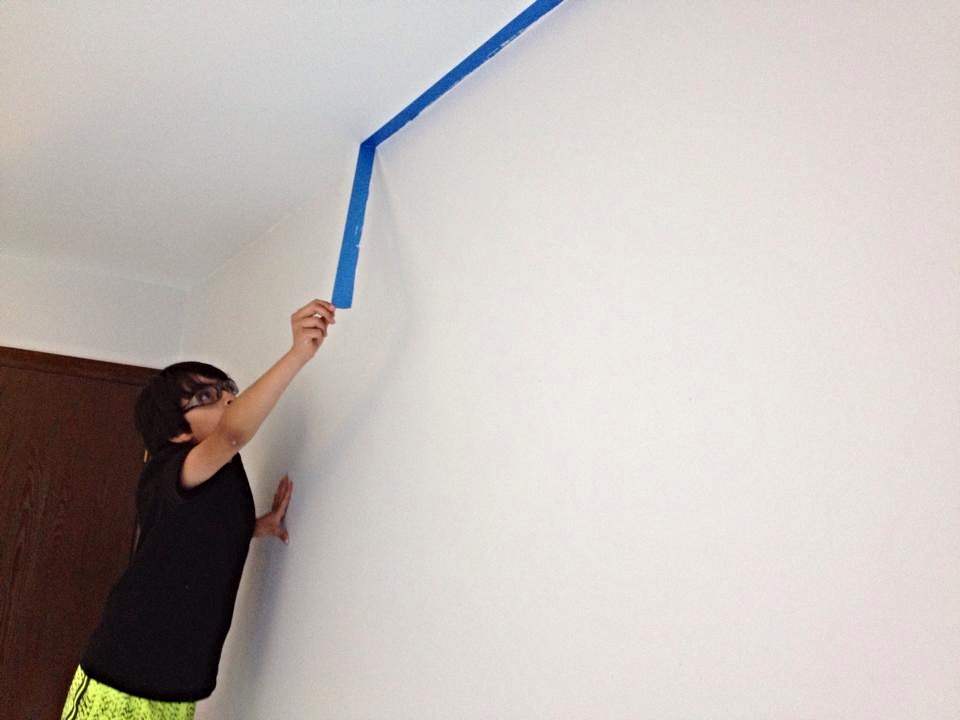  Taping off a room before painting helps create a straight edge between two different colors. Since the wall is now dry, Danny pulls the tape down and inspects the work! 