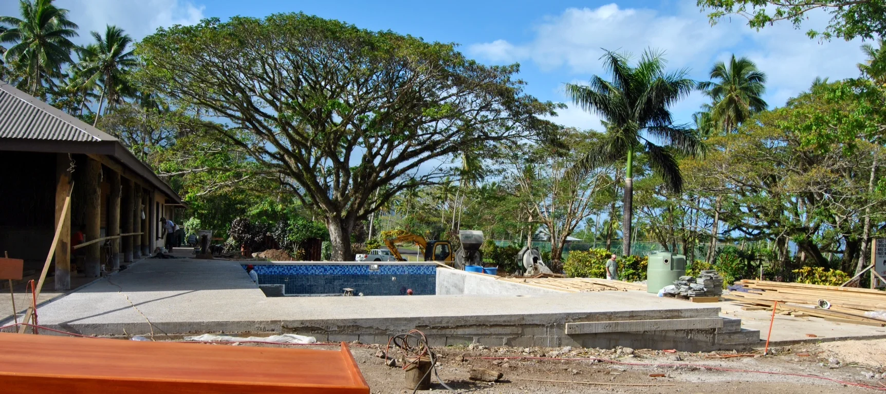 This is looking south from just outside Bure No. 1. In the foreground, our contractors are working on bed frames for the rooms. You can see a couple craftsmen working on tiling the pool. 