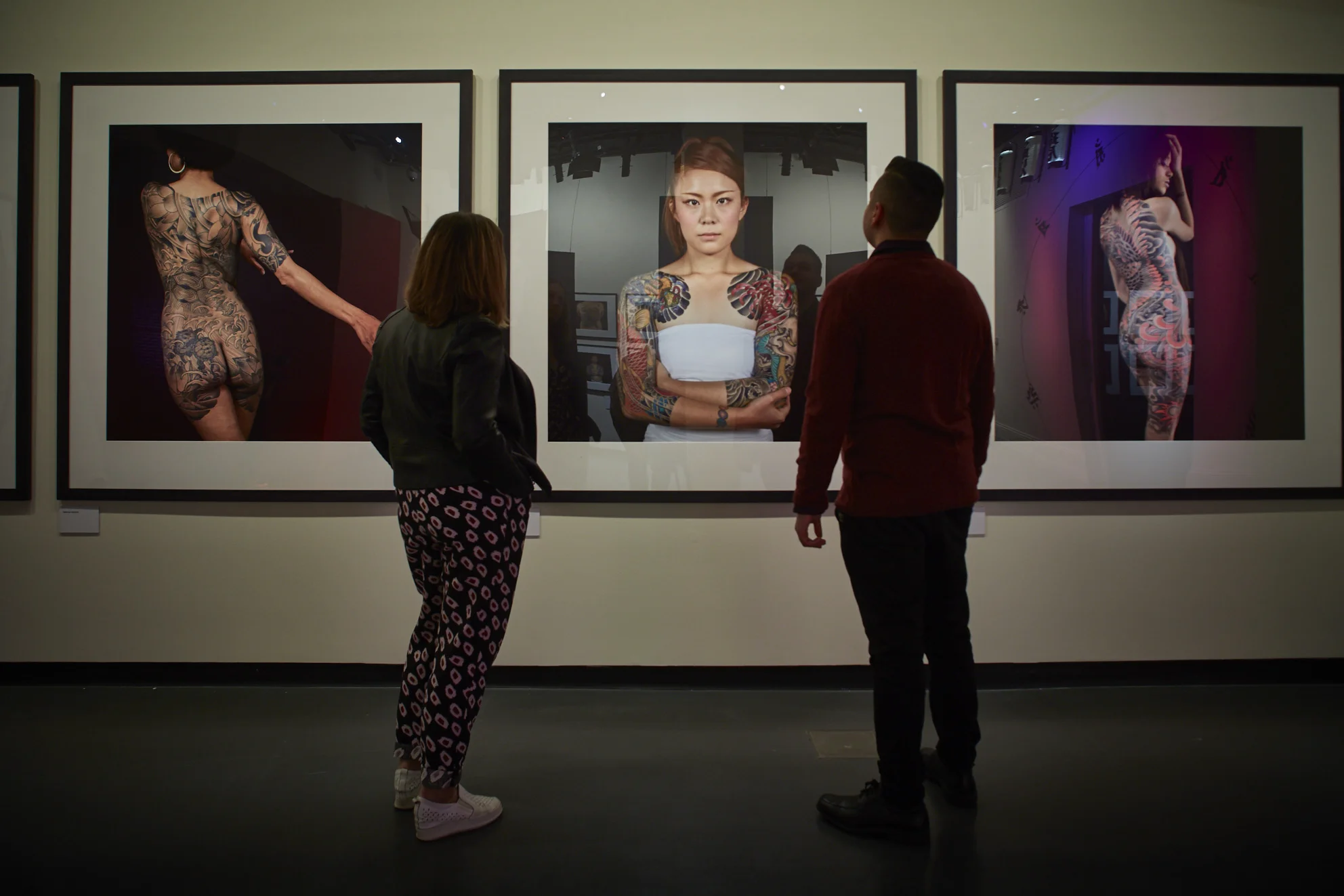 Visitors looking at photographs in Perseverance: Japanese Tattoo Tradition in a Modern World. Credit: Ben Healley.