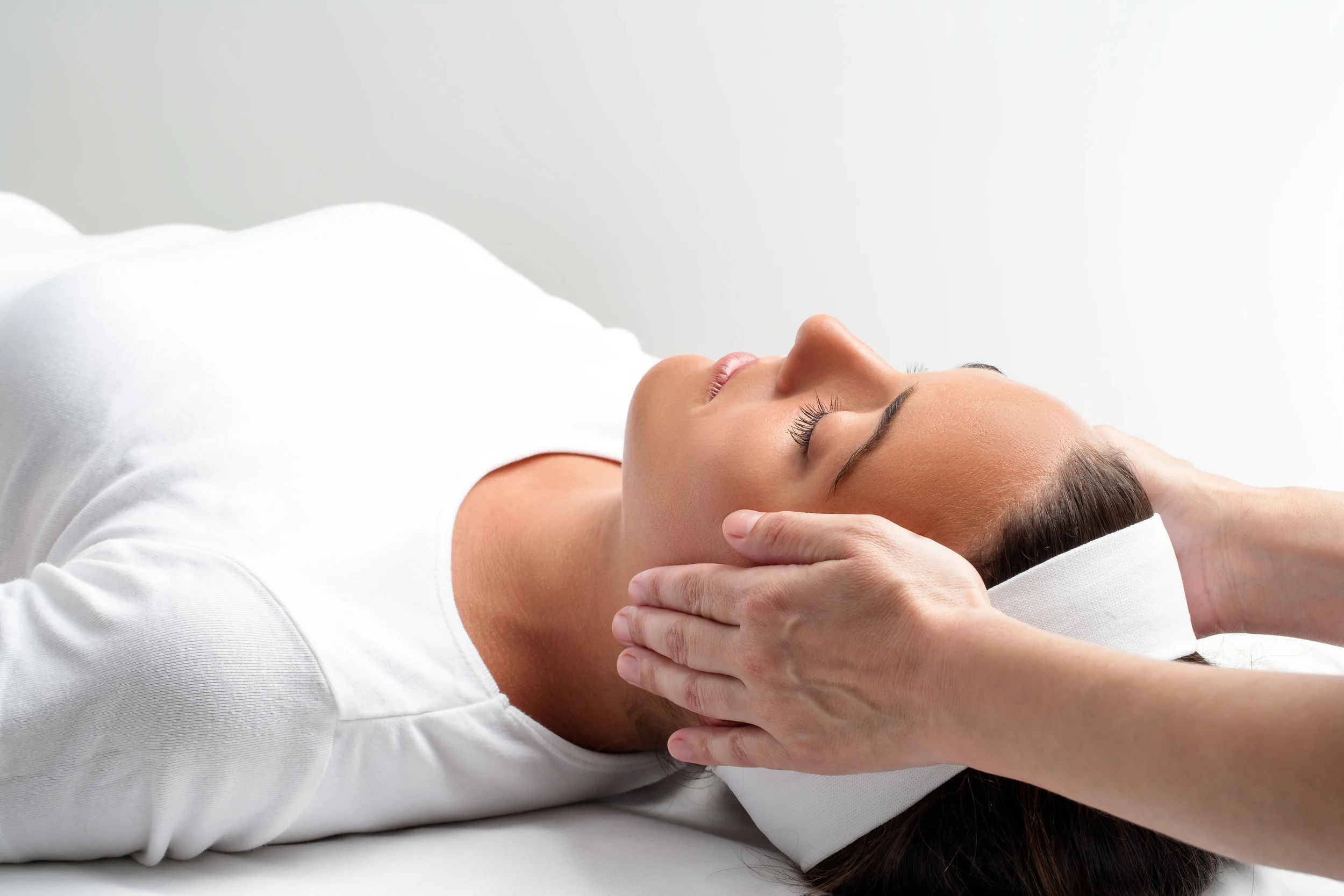 Therapist doing reiki with hands next to womans head.