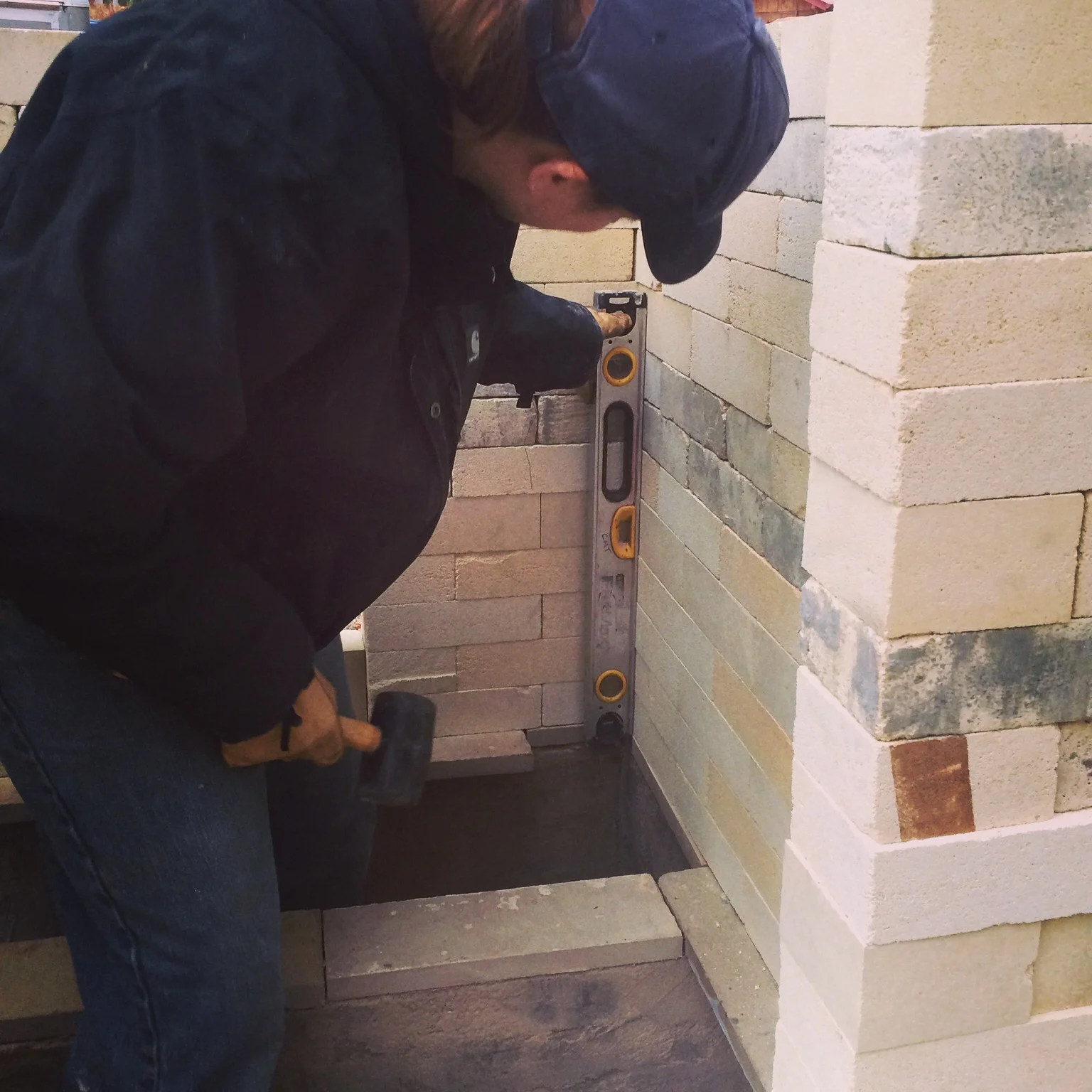 As we lay the bricks out, we ensure that we have nice straight walls by leveling them, from the inside and tapping