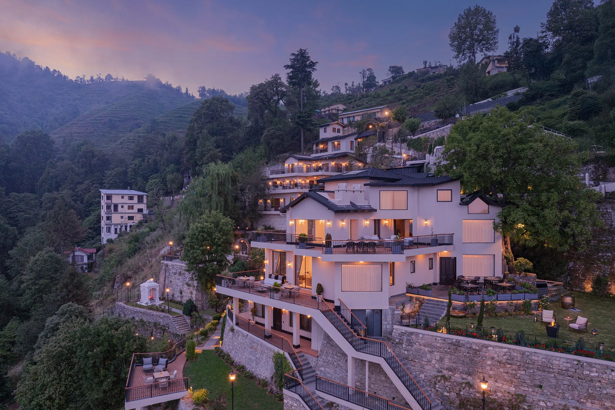 Aerial twilight view of Amaraya by Larisa in Ramgarh, a terraced hillside boutique hotel lit up against the Kumaon hills.