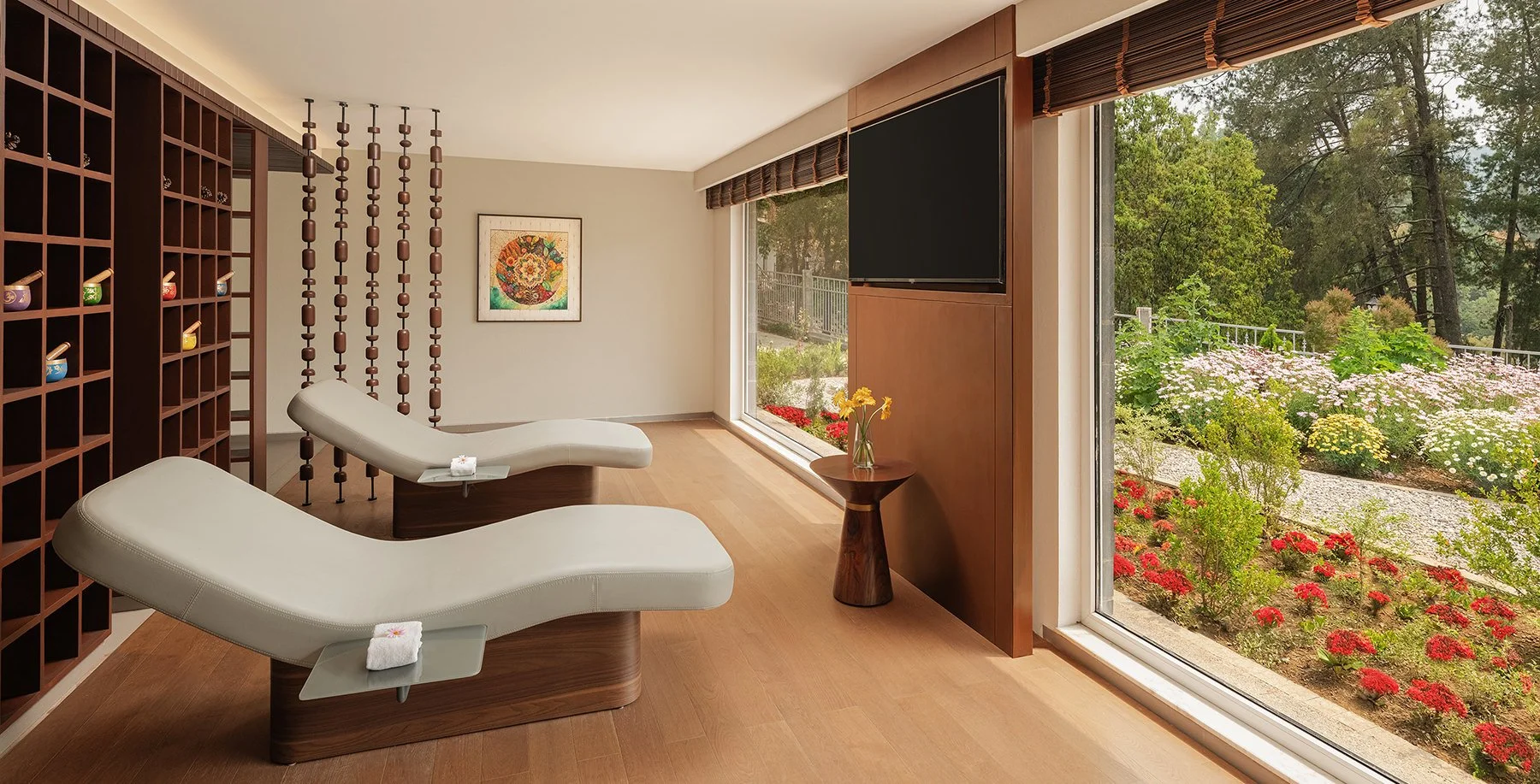 Sunlit spa treatment room at Naukuchia House with twin massage beds, floor-to-ceiling garden views, and warm wooden interiors