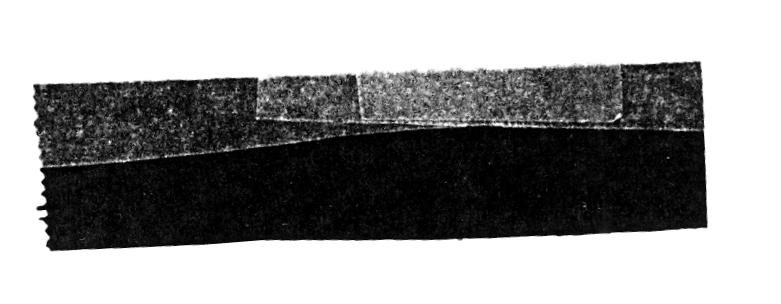 Black and white image of a series of overlapping rectangular strips of tape or material arranged in a row on a dark background.