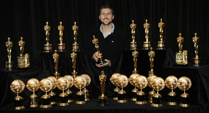 A cheesy picture of Niles with 16+ gold statues from other folks he’s been associated with.