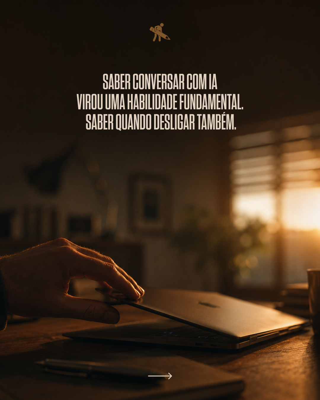 A hand opening a closed laptop on a desk in a warmly lit room during sunset, with a pen and a notebook nearby, and sunlight streaming through window blinds.