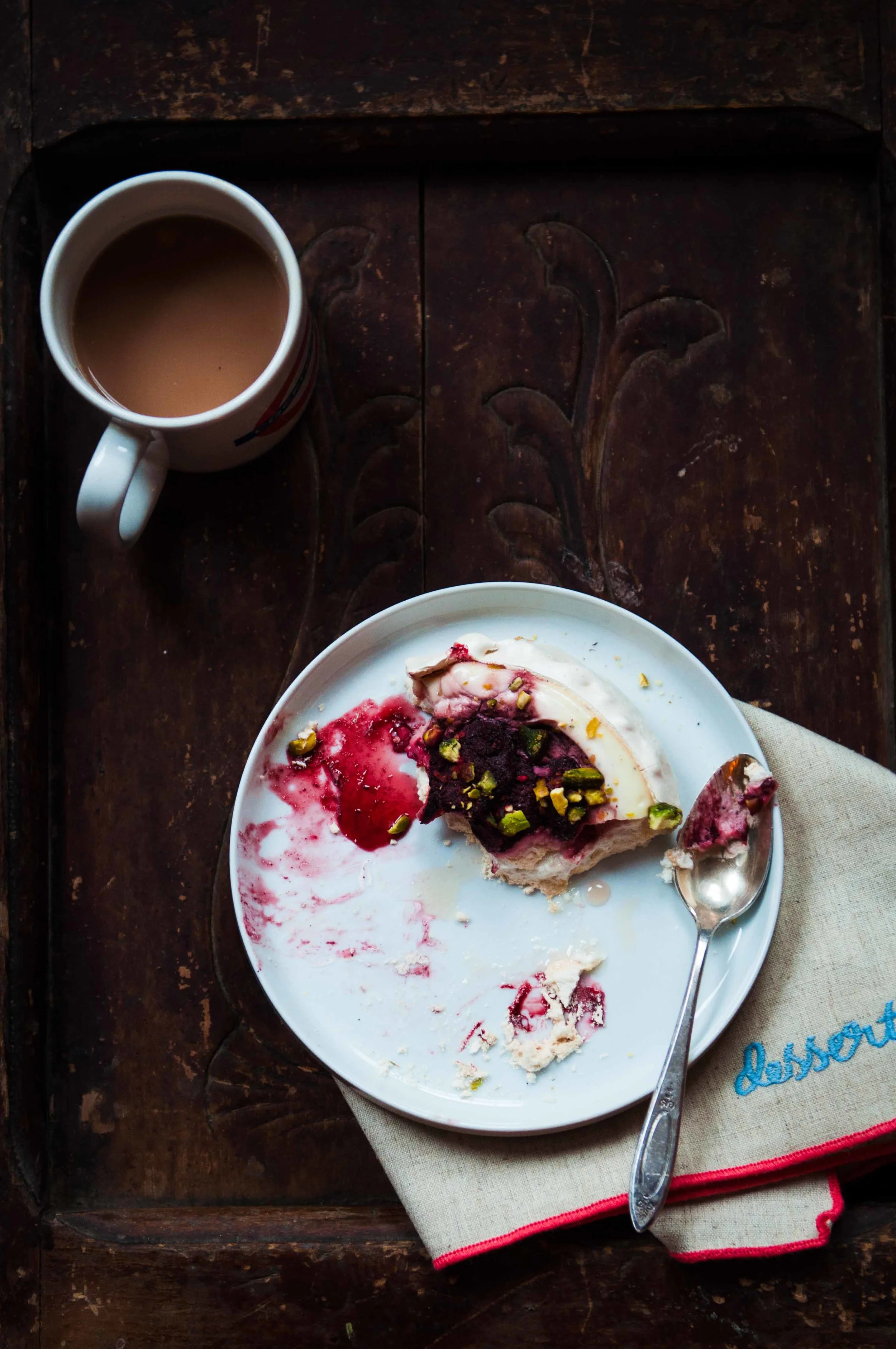 Eating a slice of cardamom pavlova filled with thick honeyed yogurt and topped with a strawberry compote made with market strawberries flash frozen from last season.