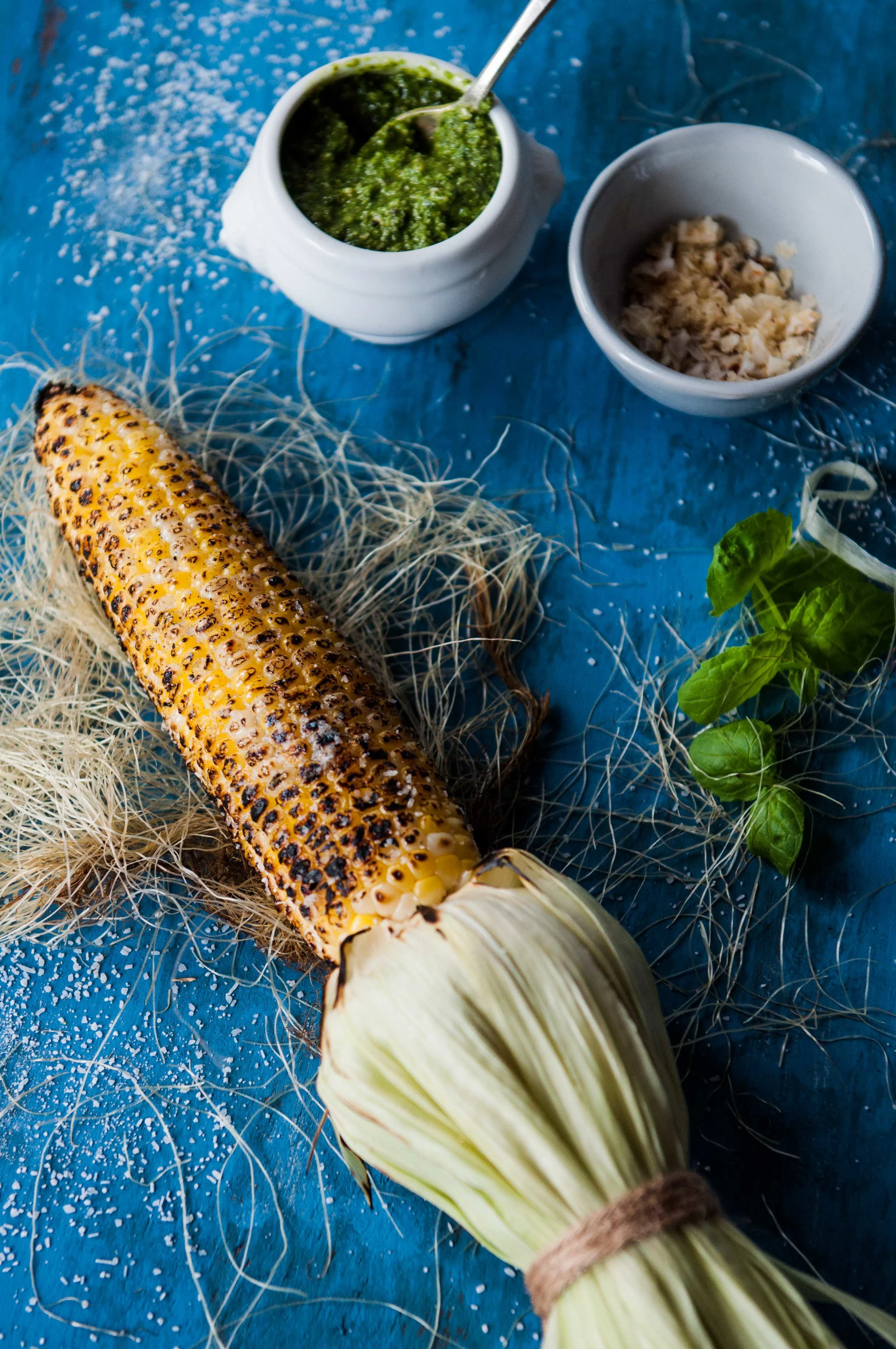 Sweet corn charred on stove and rubbed with pesto and salt.