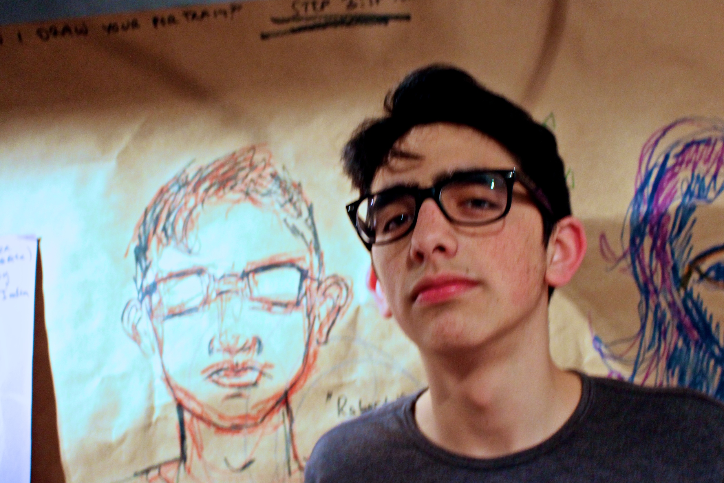  Roberto Rochin '17 poses next to a portrait drawn by Lilly Rosner '14 