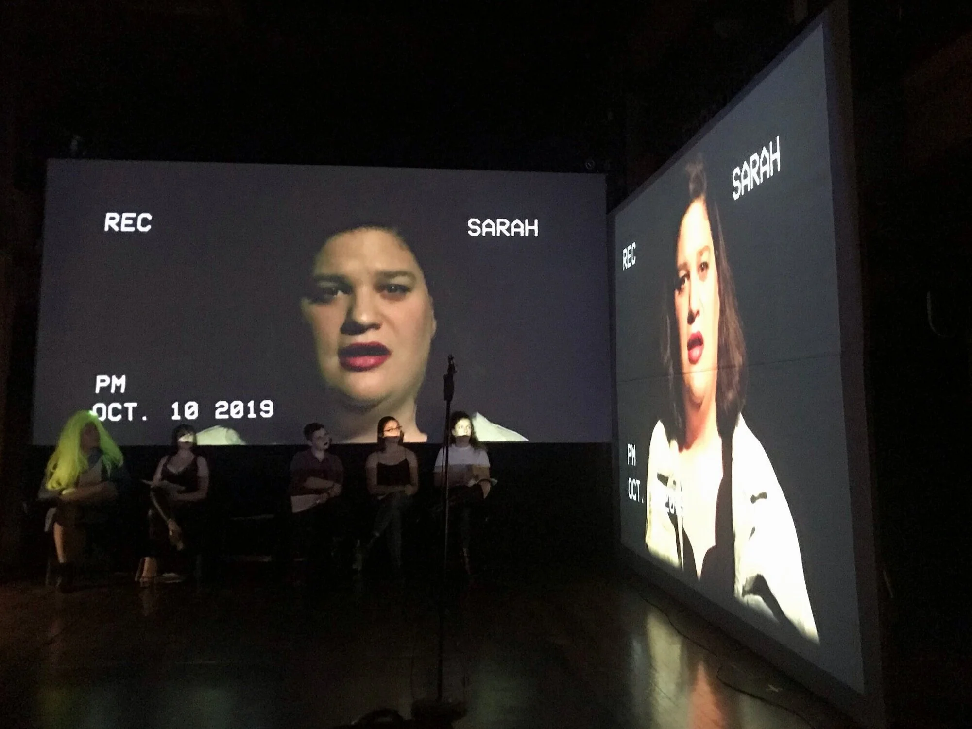 The ensemble of "I'm Very Into You" perform not only on stage in front of mics, but also in front of a camera that projects live to two perpendicular projection screens. In front of camera. Pictured: Sarah Sterling, MFA’21Credit: Hallie Riddick