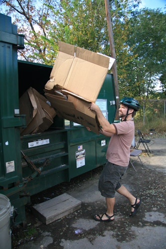 Dumping cardboard into the recycling dumpster.