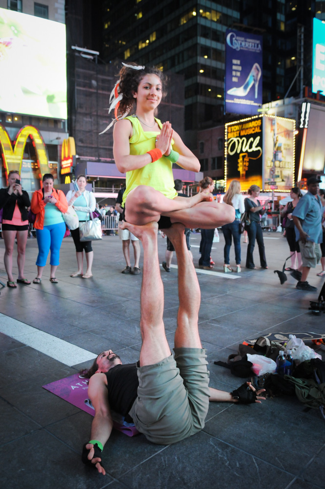 Acroyoga after dark in Times Square with Elana Jaroff performing lotus on the feet of her base