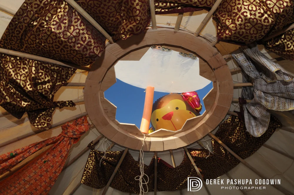 A floating monkey balloon peeks in through the hole at the top of our yurt at Spiral Monkey Camp