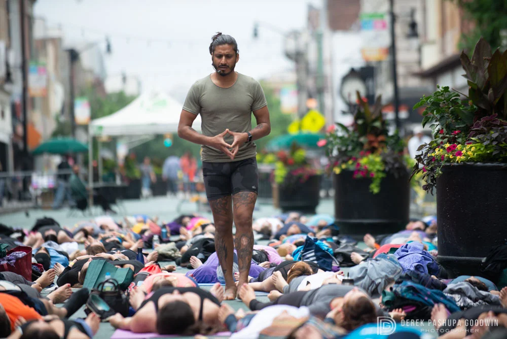 Teacher Jai Sugrim walks amongst students resting in shavasana; Yoga Fest Jersey City