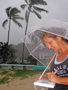 Kirsten working on a project in a passing rain squall. Lanikai, Oahu
