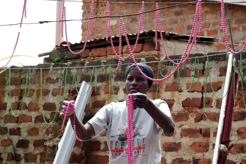 Evelyn hangs strings of freshly painted beads to dry in her backyard.