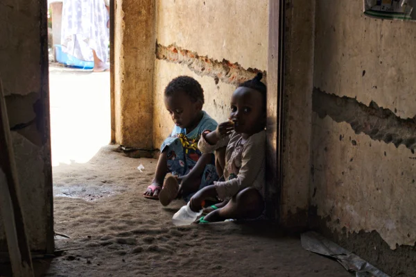 Mario and Mari play in their home as their mother makes beads one afternoon.