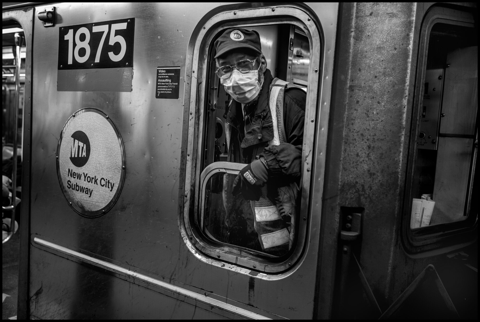  As I stood in the train station at Times Square, a south bound #3 train arrived in the station. The train conductor leaned out the train and said to me, google me, I am know as “the happy conductor”.  March 21, 2020. © Peter Turnley.  ID# 01-003 