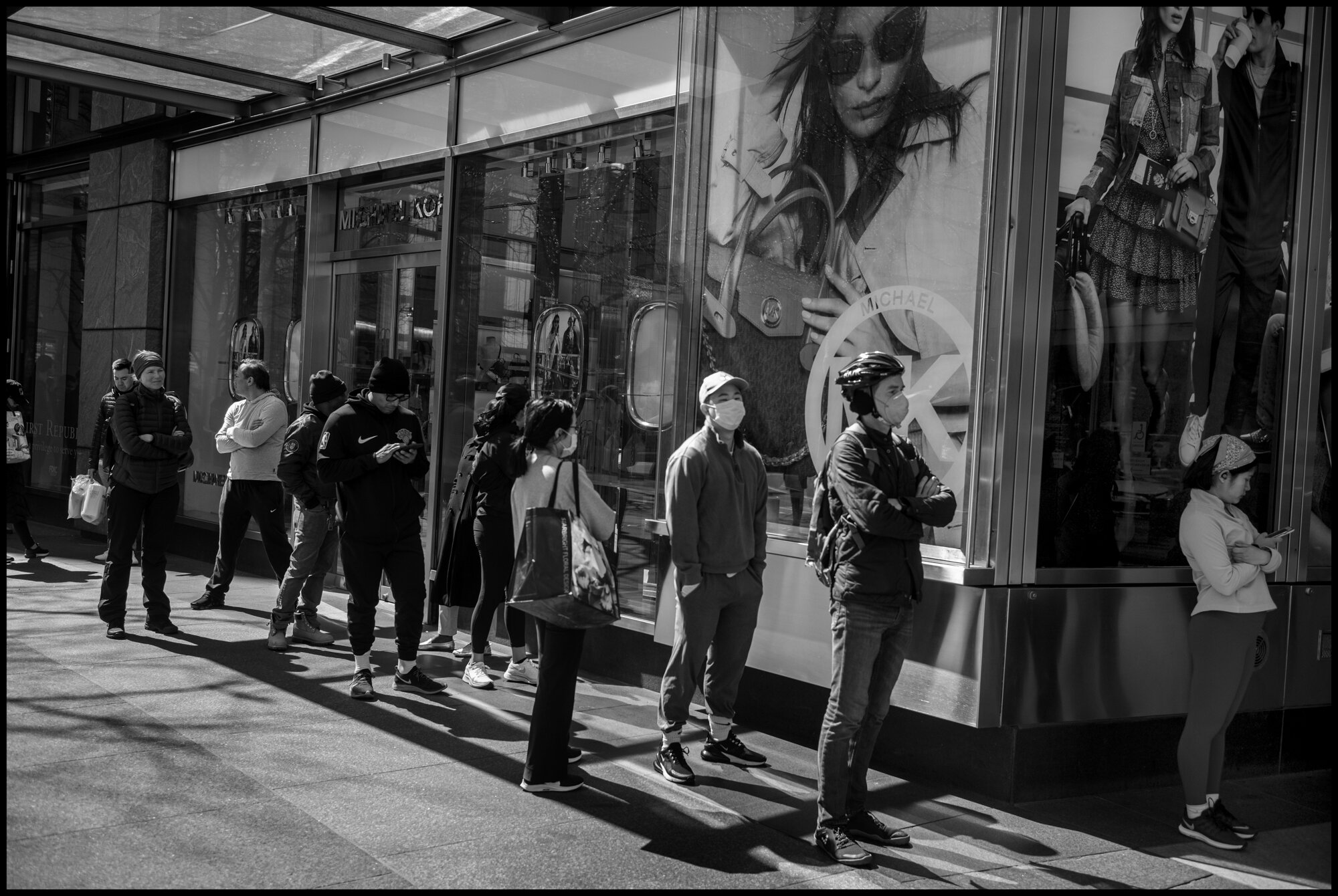  Many masked people waited in line to enter the shopping mall at Columbus Circle.  March 21, 2020. © Peter Turnley.  ID# 01-008 