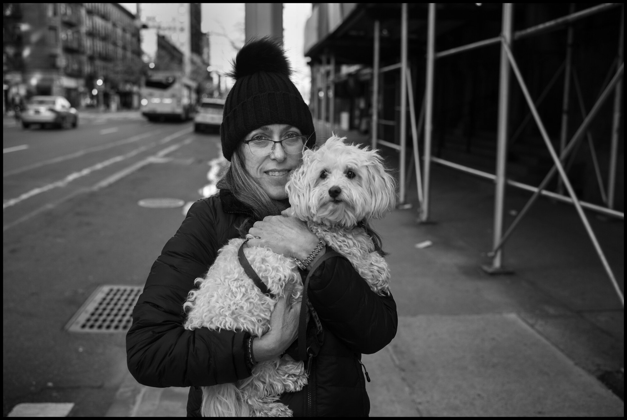  Loren crosses the street with her dog Molly while out for a walk on Amsterdam Avenue on the Upper Westside.   March 24, 2020. © Peter Turnley.&nbsp;  ID# 03-003 