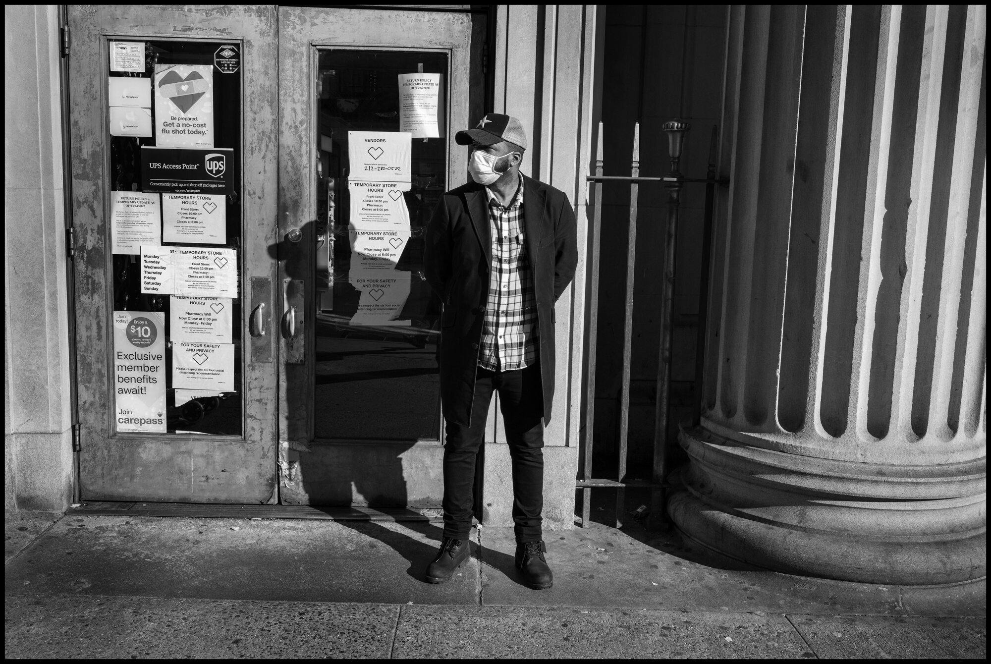  A man stands in front of a CVS pharmacy on Amsterdam Ave., indicating to people standing in line, all 6 feet a part, when they can enter one by one, the pharmacy.&nbsp;  March 24, 2020. © Peter Turnley.  ID# 03-010 