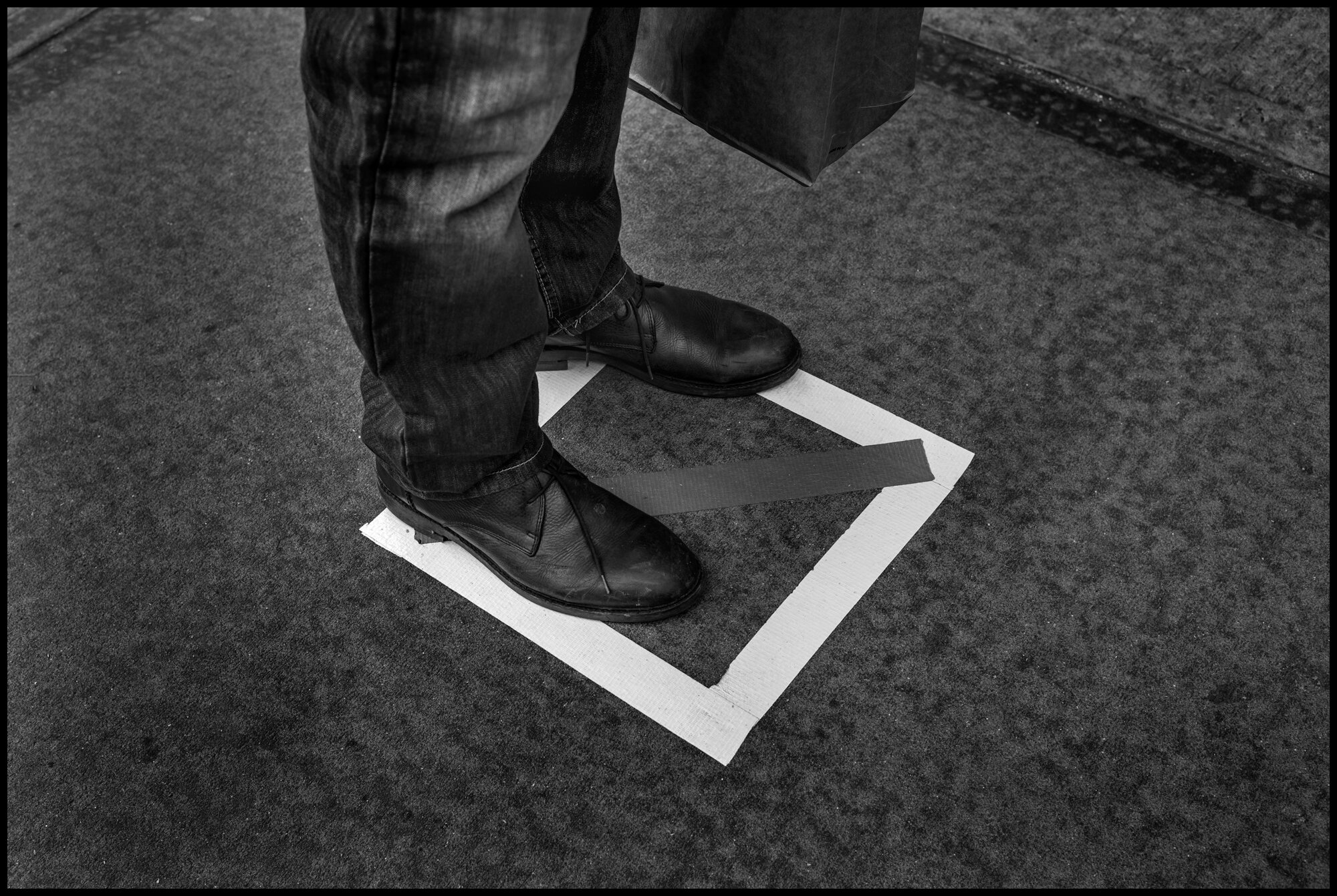  During this time of social distancing, in front of many stores in New York, one can find squares, suggesting a safe 6 foot distance between shoppers, waitng to enter a store. Here a man waits to enter Zaybars’ on the Upper Westside.  March 31, 2020.