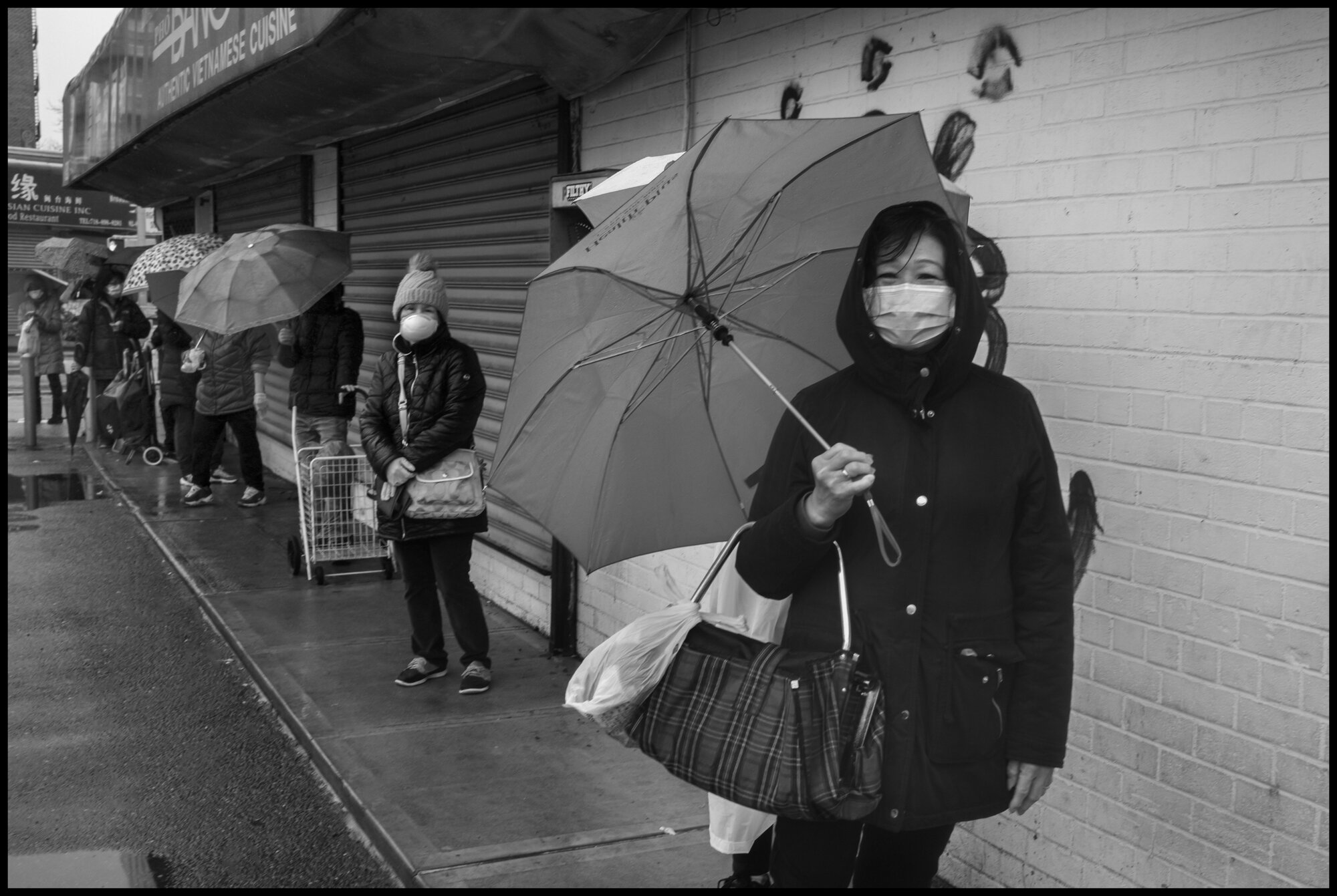  Many people, mostly immigrants from China, wait with social distance between each other, to enter a Chinese supermarket in Queens near Elmhurst Hospital.   March 31, 2020. ©Peter Turnley.   ID# 09-009 