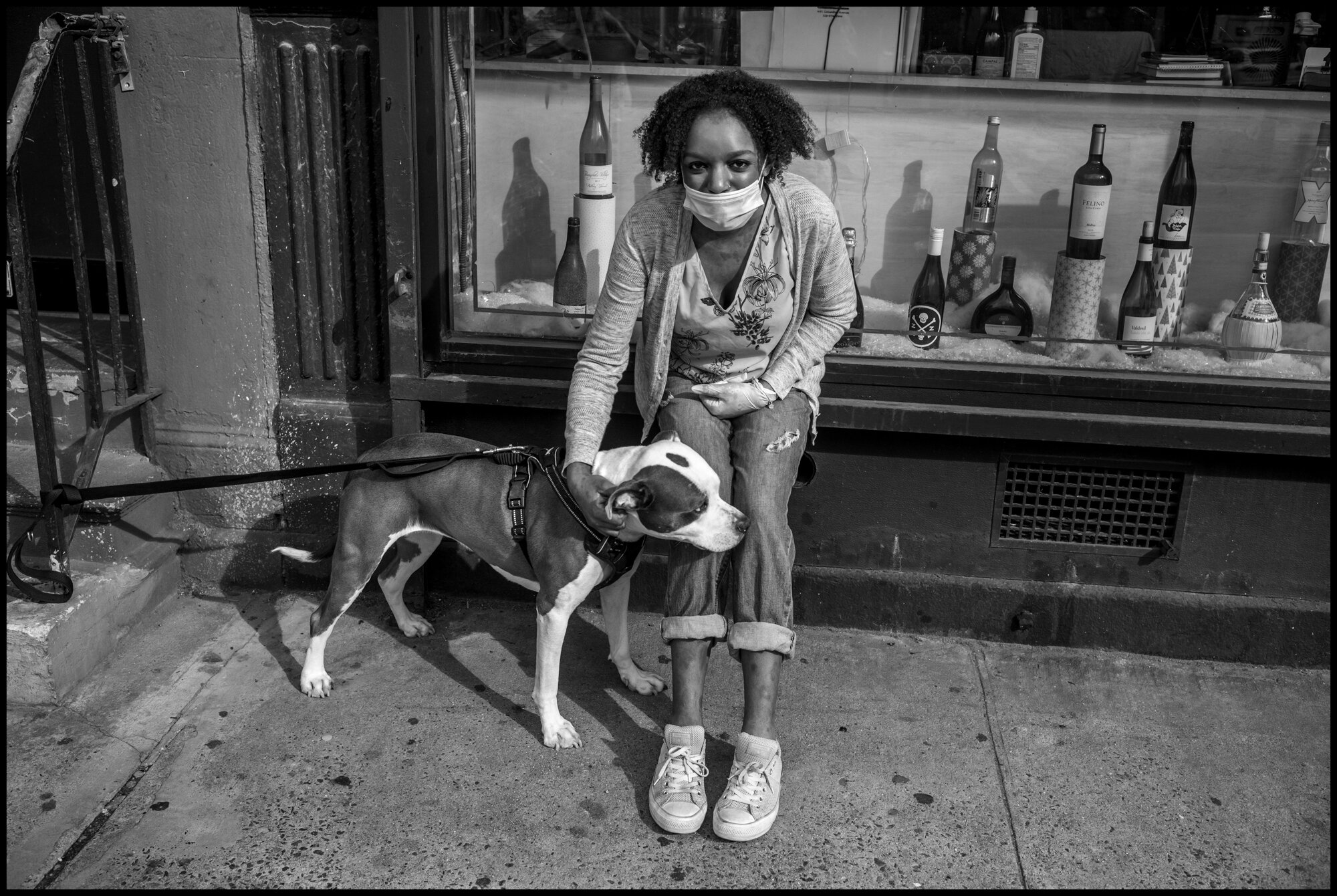  Danielle, an assistant general manager at West Side Wines watches over Callie, a street rescue dog that belongs to Matt, who was inside purchasing some wine. Danielle explained that business is up at the wine store since the beginning of this crisis