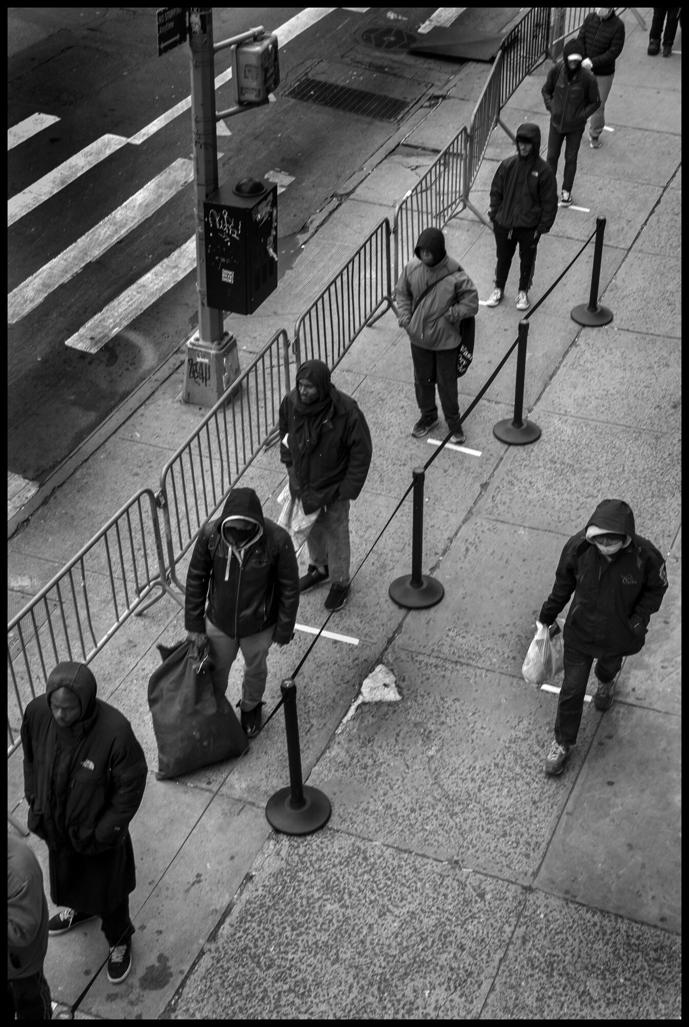  Hundreds of people, homeless or vulnerable without food during this time of the coronavirus crisis, wait outside in the cold, to receive a bag of food at The Bowery Mission in New York City.  April 10, 2020. © Peter Turnley  ID# 18-002 