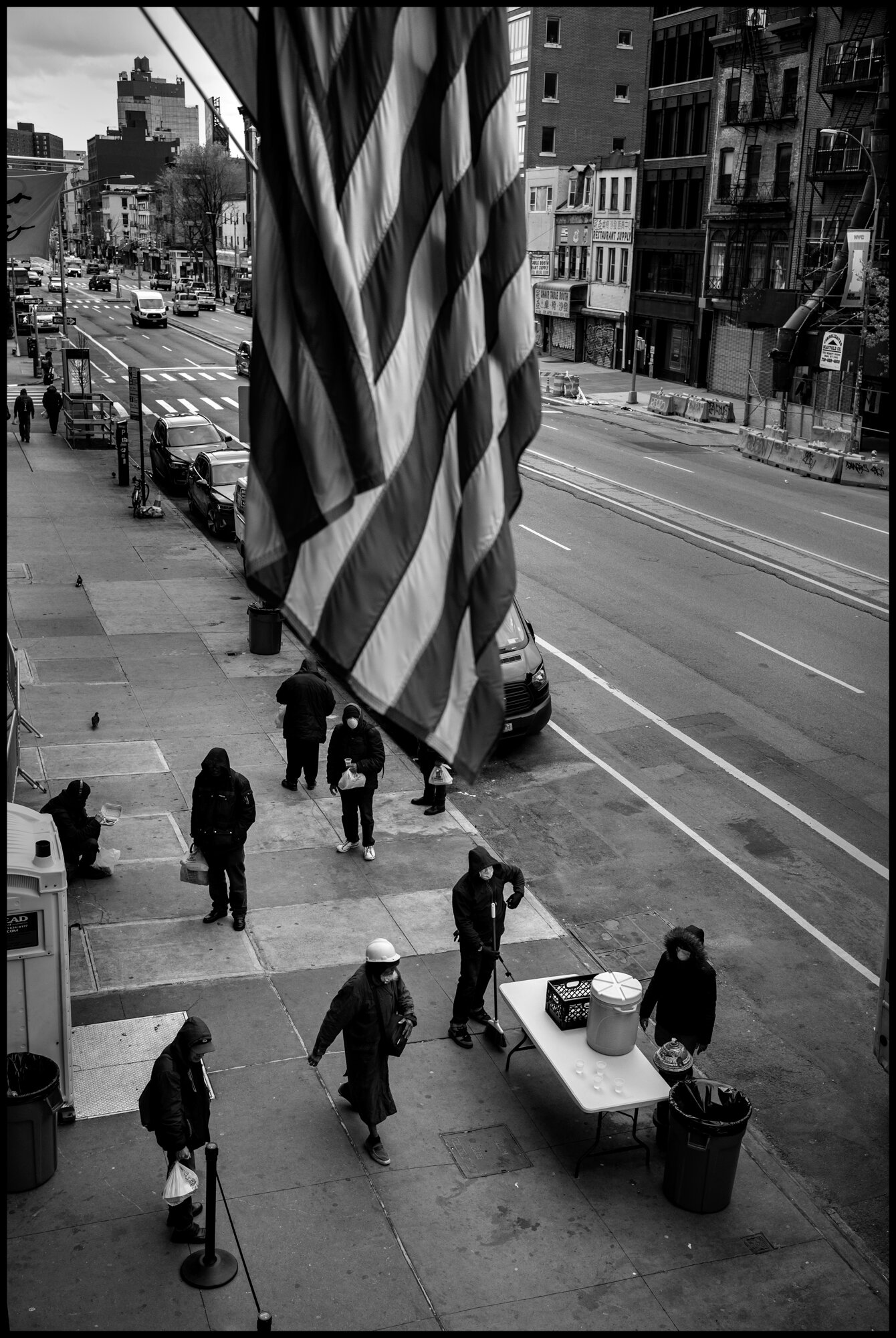  People in need of food, at the time of this coronavirus crisis, stand in line waiting to receive a bag of food at The Bowery Mission.  April 10, 2020. © Peter Turnley  ID# 18-006 