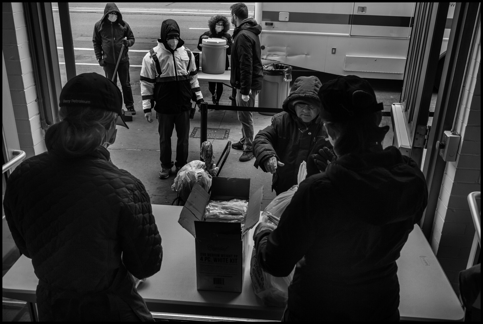  Volunteers hand out bags of food to homeless people or people without the means to buy food at this time, at The Bowery Mission in New York City.  April 10, 2020. © Peter Turnley  ID# 18-017 