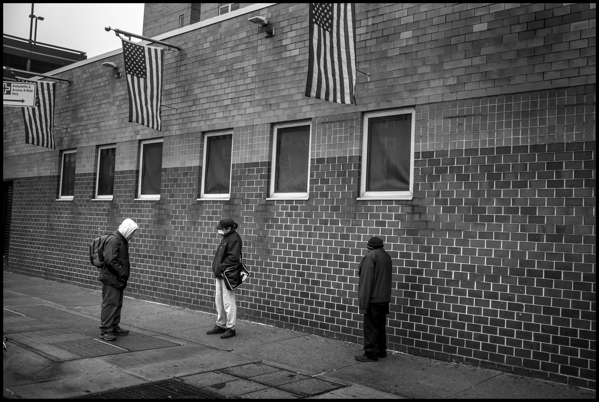  Men stand outside Elmhurst Hospital in Queens, one of New York’s hospitals with the largest number of coronavirus patients.   March 29, 2020. © Peter Turnley.   ID# 07-022 