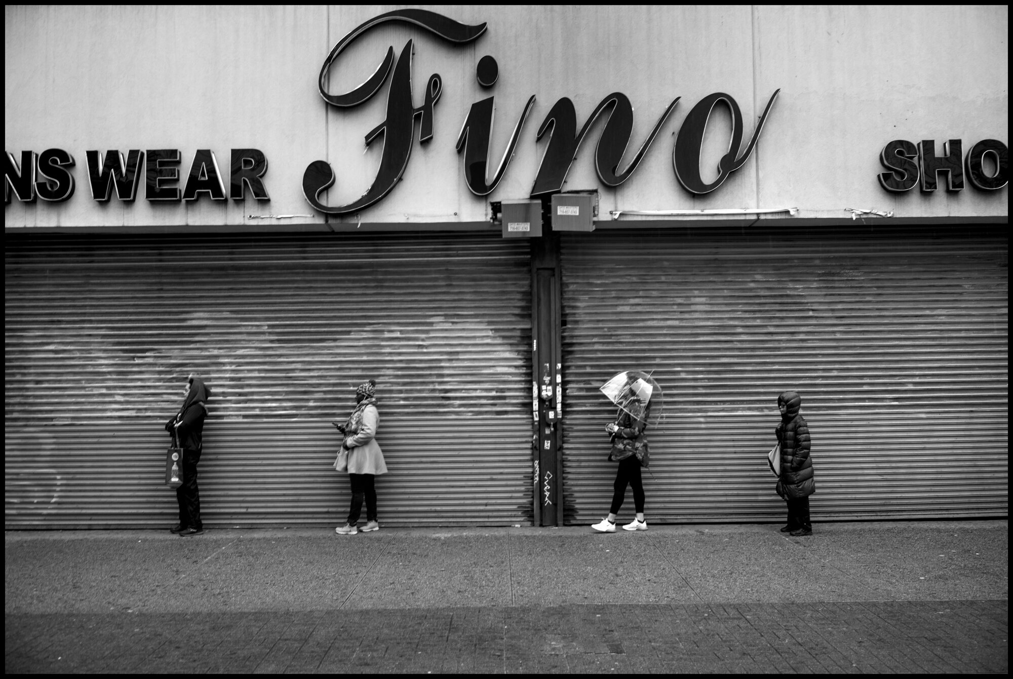  People social-distance in front of a store on 125th Street in Harlem.   March 28, 2020. © Peter Turnley.   ID# 06-007 